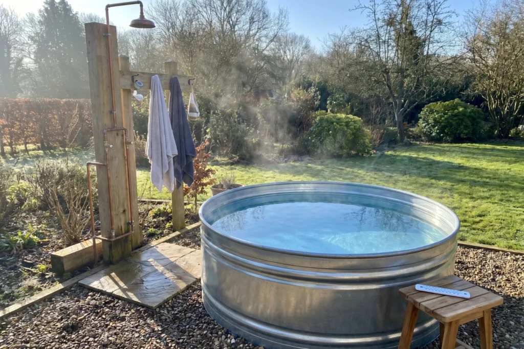 Galvanized stock tank cold plunge beside outdoor shower for backyard bathroom contrast therapy