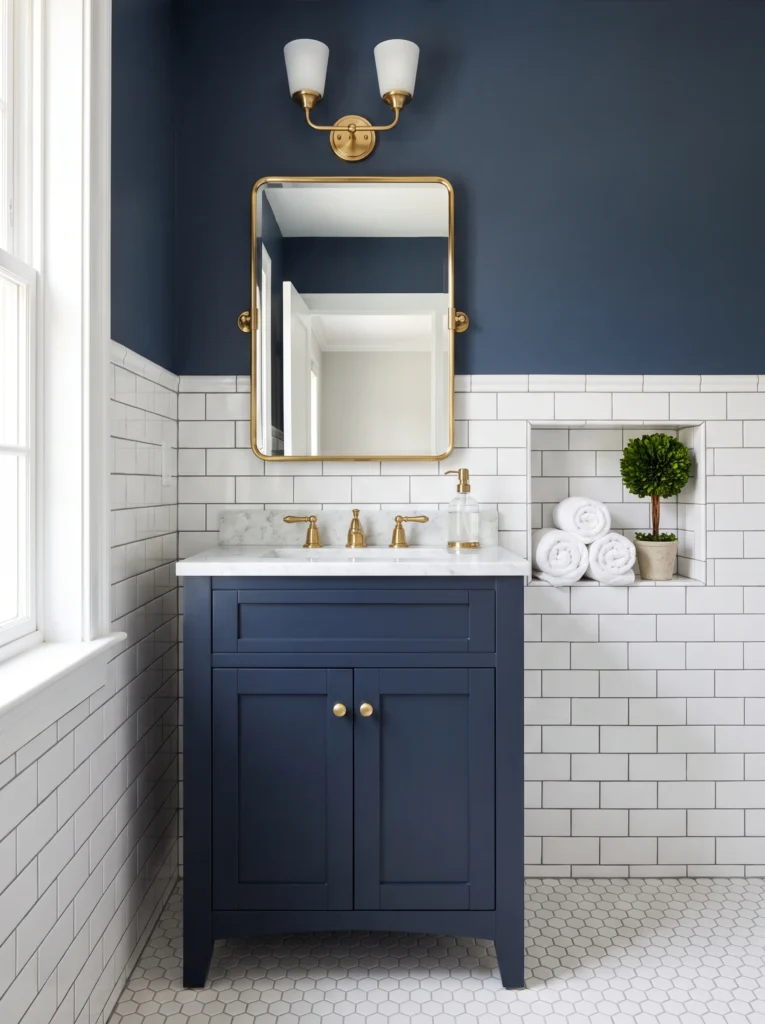classic guest bathroom with navy upper wall, white subway tile, navy shaker vanity, brass pivot mirror, and towel niche