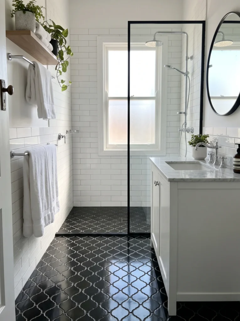White subway tile bathroom with black arabesque floor tile and a black framed shower screen