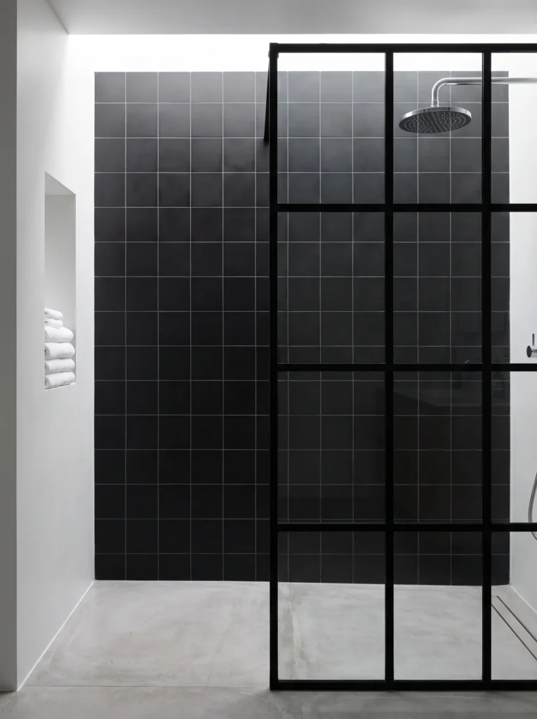 Matte black square tile wall and black grid shower screen over a polished concrete bathroom floor