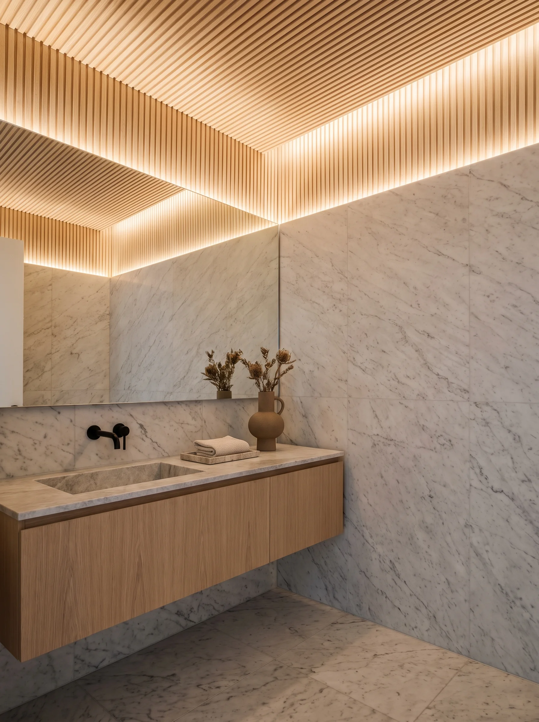 Modern marble bathroom with a slatted oak ceiling, cove lighting, full height marble wall tile and oak floating vanity