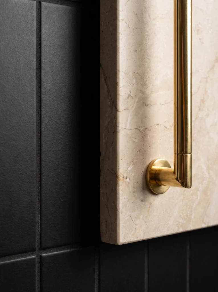 close up of matte black tile next to honed stone and a polished brass handle