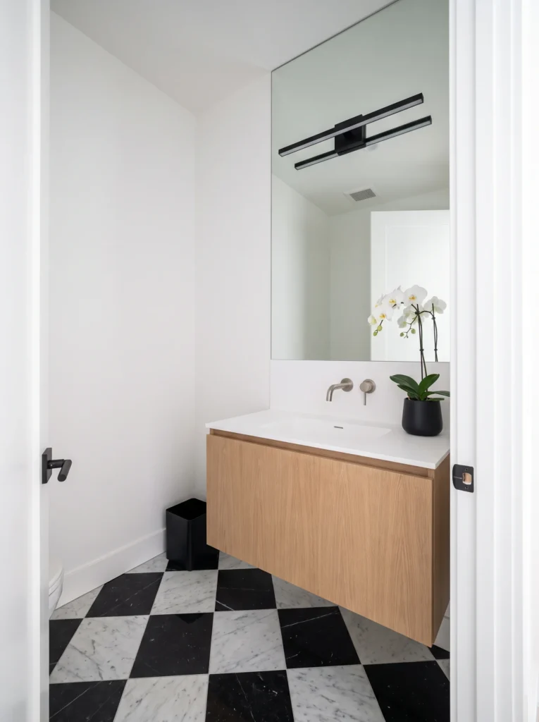 black and white marble checkerboard floor powder room with floating oak vanity and black linear light
