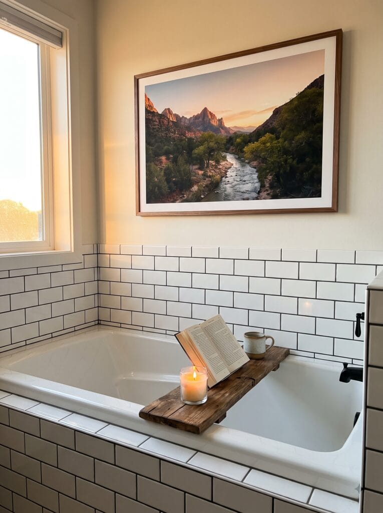 Framed landscape photograph hanging above a subway tiled bathtub