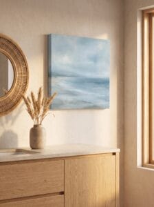 Unframed stretched canvas seascape above a wooden bathroom vanity