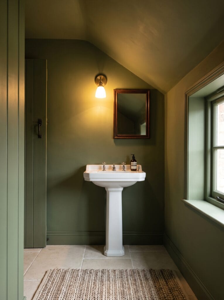 Bathroom painted entirely in one muted olive including ceiling, door and skirting