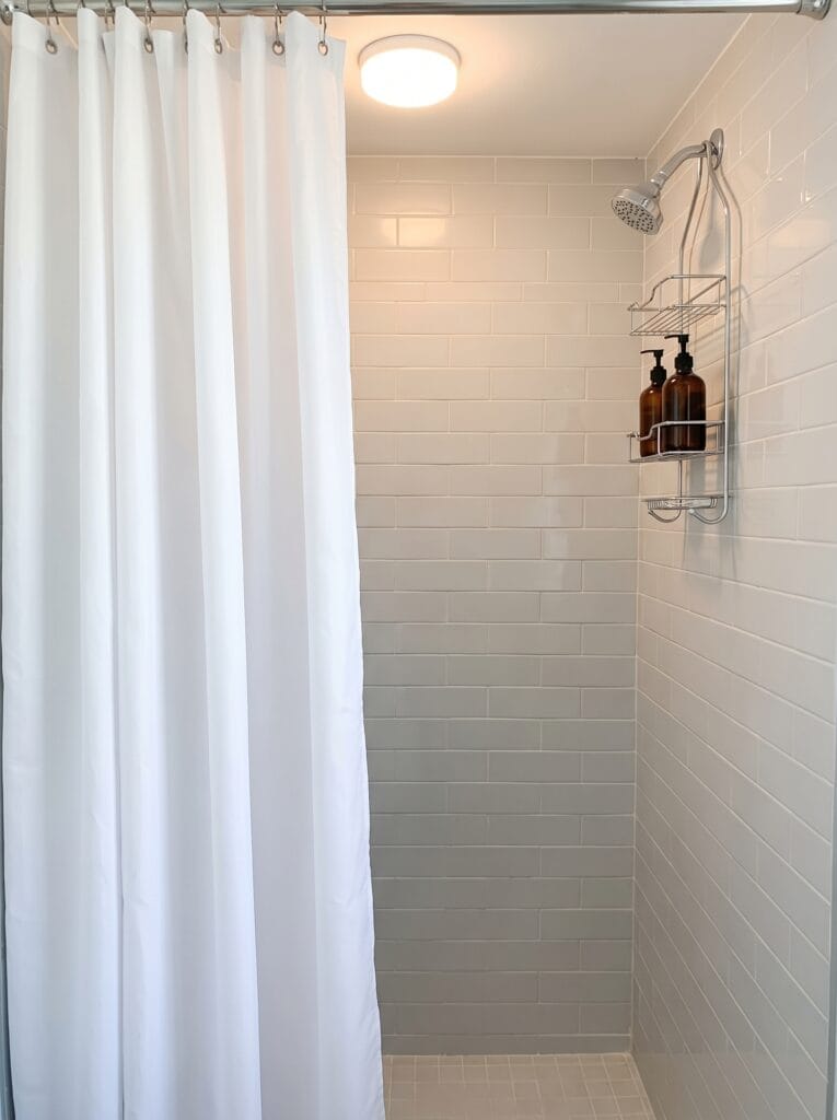Plain white polyester shower curtain in a compact windowless bathroom