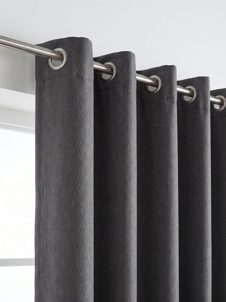 Close view of a charcoal curtain with brushed silver grommets on a steel rod