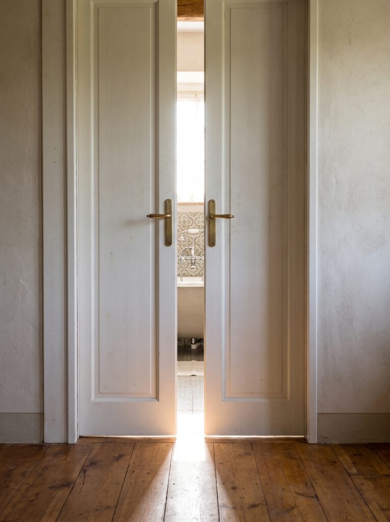 Pair of white panelled doors meeting in the centre of a wide bathroom opening