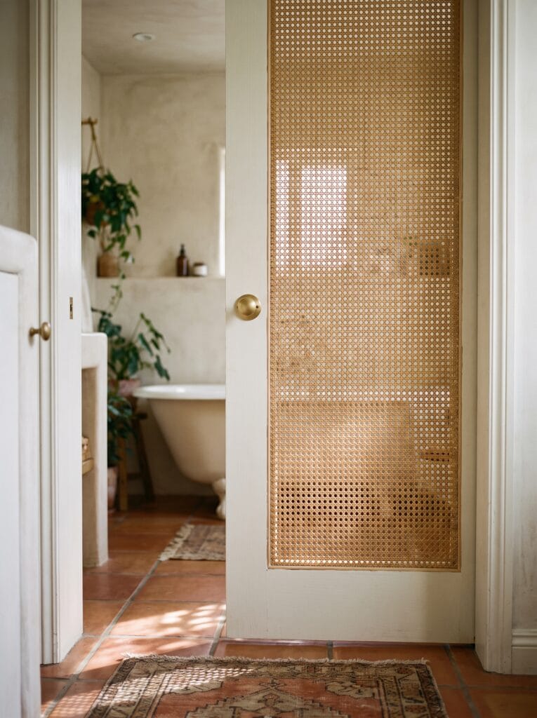 Bathroom door with a woven cane rattan panel set into a painted frame
