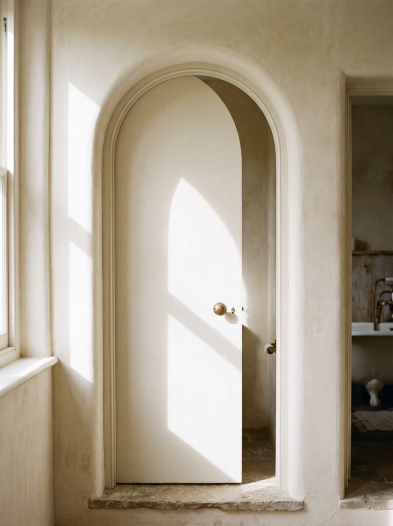 Bathroom door with a gently arched top set into a matching arched plaster opening