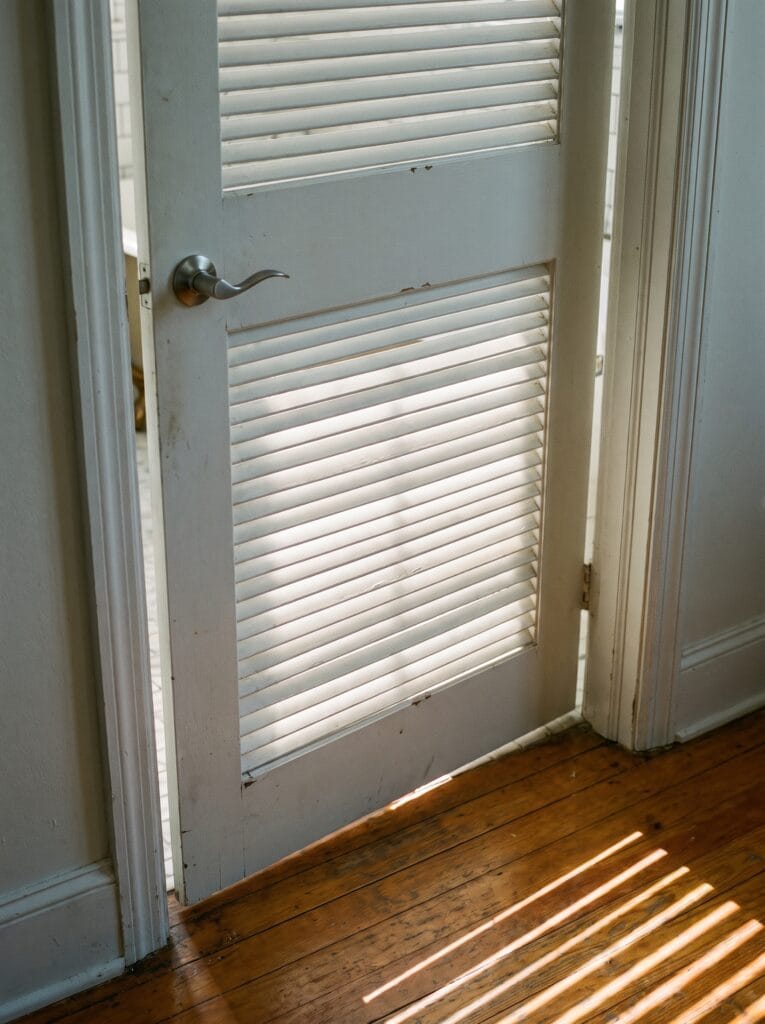 White painted louvred bathroom door with angled horizontal slats