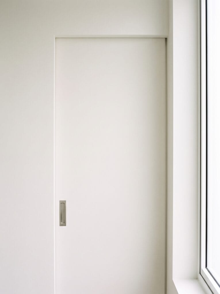 Perfectly flat flush white bathroom door with a recessed handle