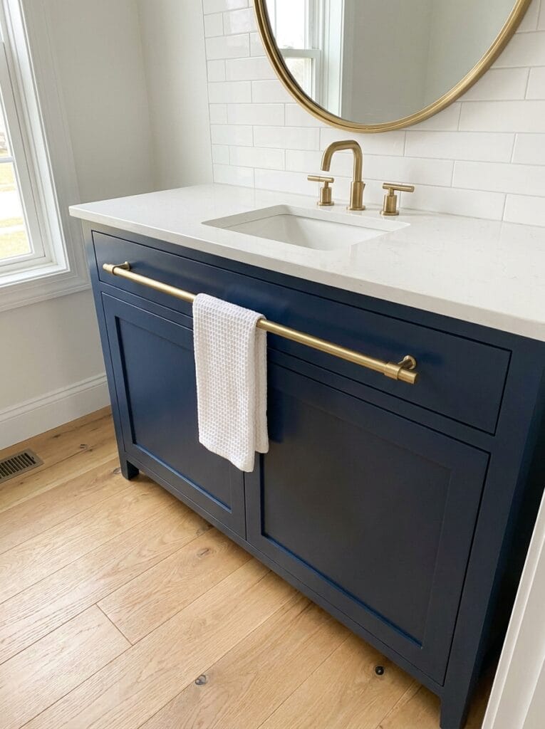 Navy shaker vanity with a long brass bar pull on the top drawer holding a white waffle hand towel