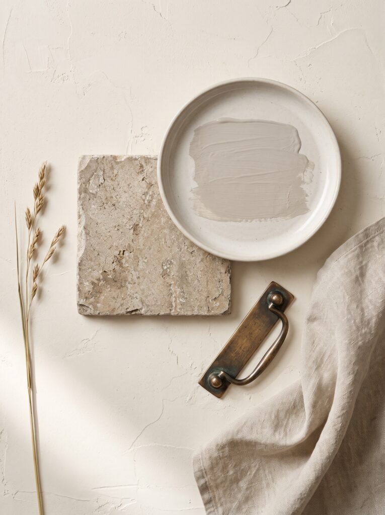 organic bathroom material board with limewash paint swatch, rough stone tile and an aged bronze pull