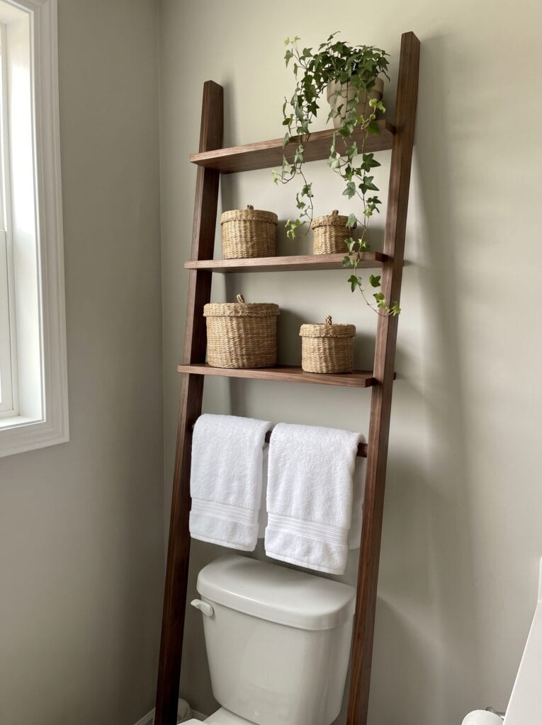 walnut ladder shelf over a toilet with seagrass baskets and two white towels