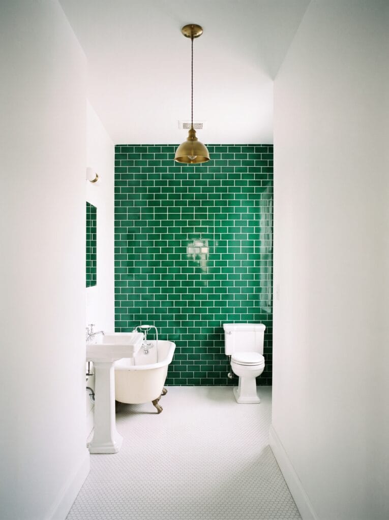 Narrow bathroom with emerald green subway tile on the back wall only