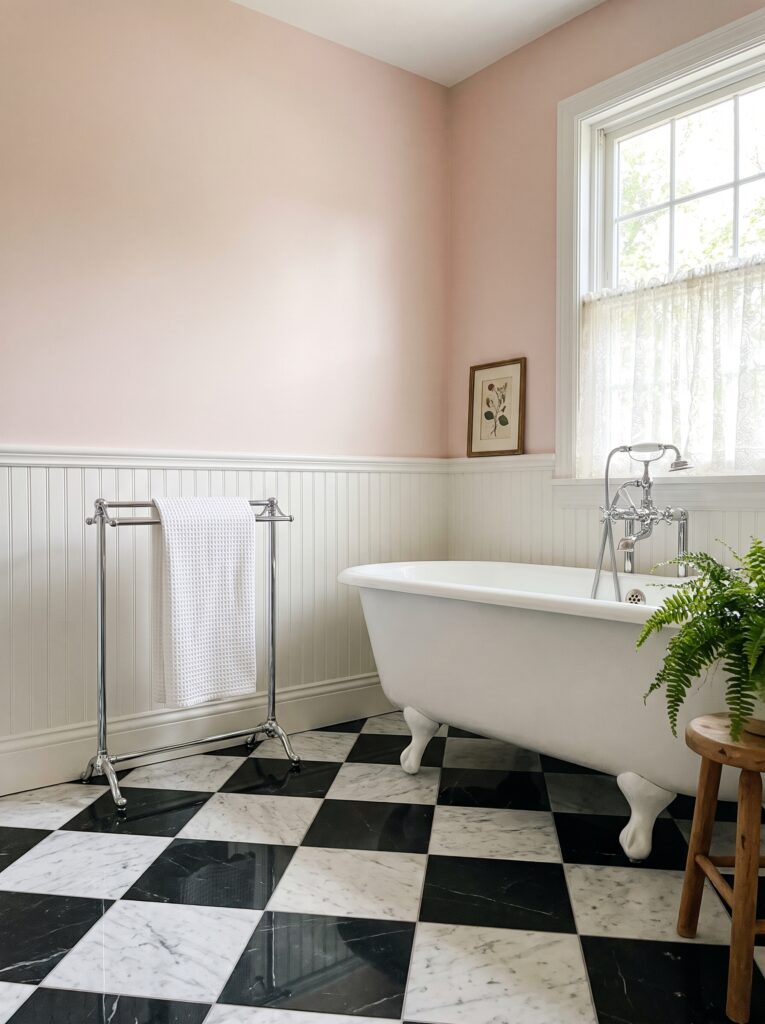 diagonal black and white marble checkerboard floor in a blush pink vintage bathroom with a clawfoot tub