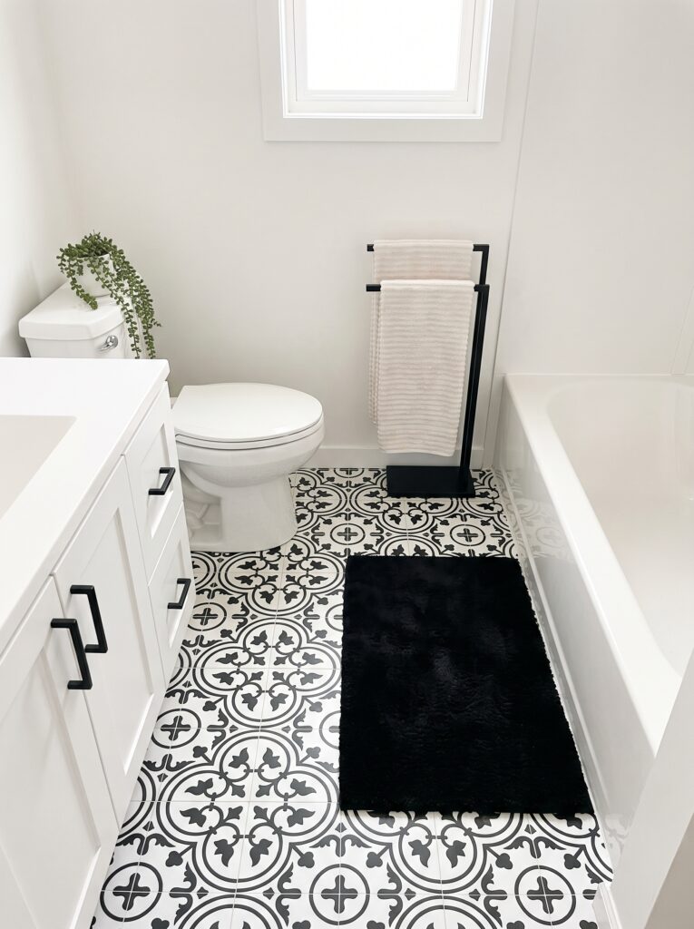 black and white Moroccan peel-and-stick vinyl floor tiles in a white rental bathroom