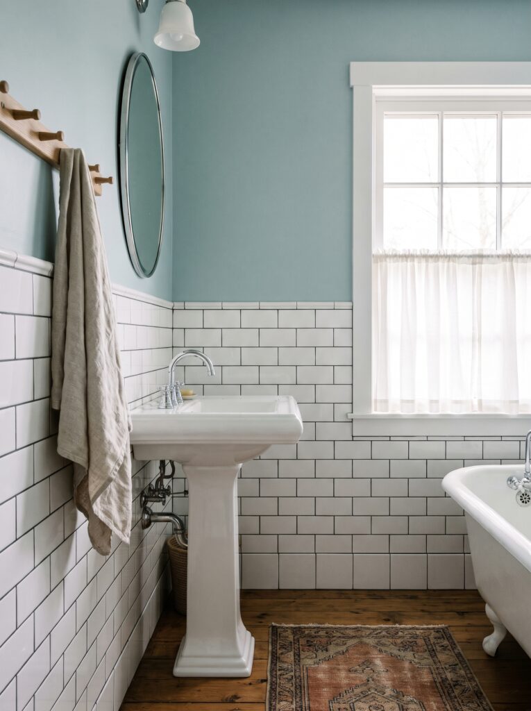 white subway tile wainscoting below duck egg blue paint in a cottage bathroom with a pedestal sink