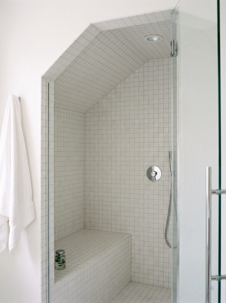 small white matte square tile continuing from the walls across a sloped steam shower ceiling