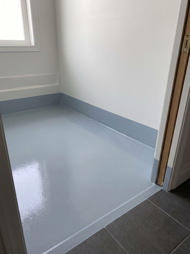 gray-blue waterproofing membrane running up the bathroom wall and across the doorway threshold