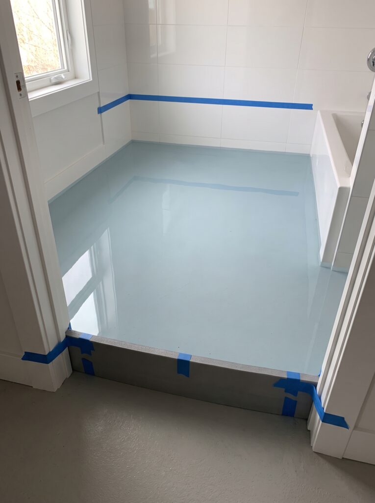 gray foam dam taped across a bathroom doorway for a flood test on the cured membrane floor