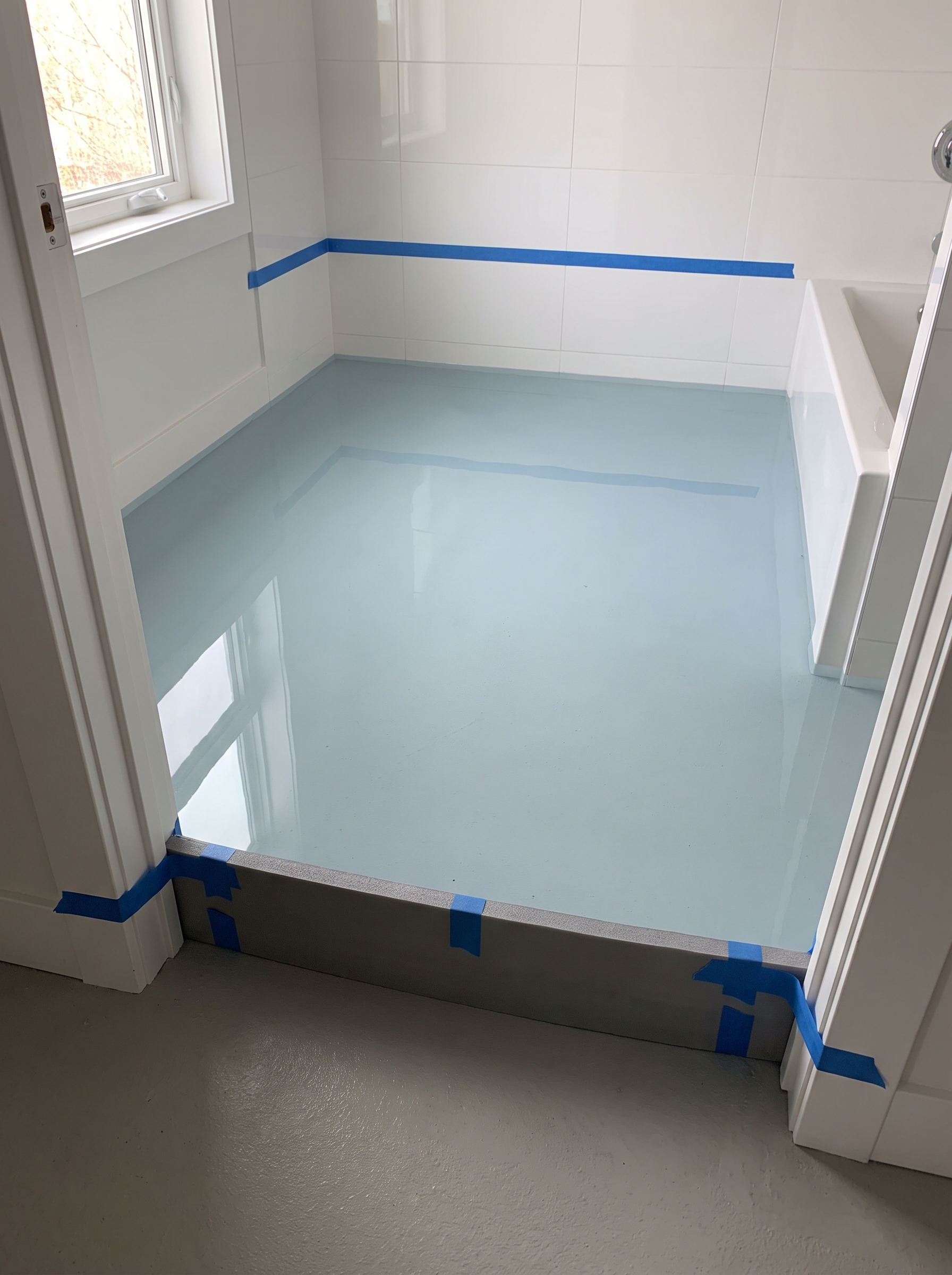 gray foam dam taped across a bathroom doorway for a flood test on the cured membrane floor