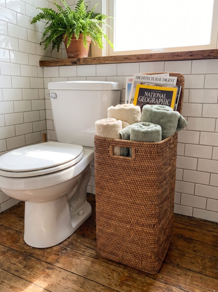 woven basket on floating shelf above a bathtub holding candles and a small plant