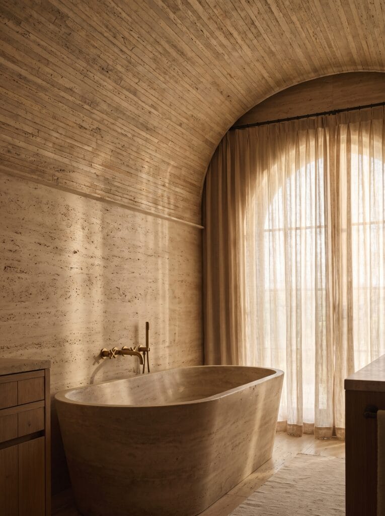 arched doorway framing backlit travertine alcove tub with candles